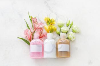 Bottles of shampoo and flowers on light background�