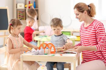 Nursery teacher with cute little children in kindergarten�