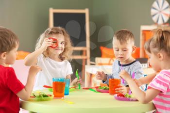 Cute little children eating tasty lunch in kindergarten�