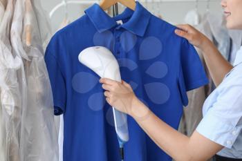 Woman steaming clothes in modern dry-cleaner's�