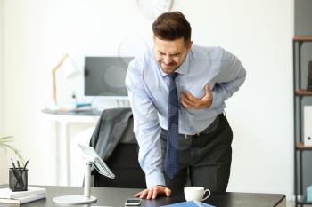 Young businessman having heart attack in office�