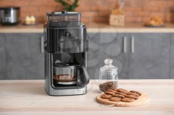 Modern coffee machine with cookies on table in kitchen�