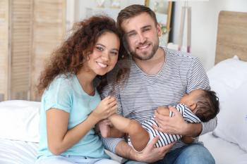 Portrait of happy interracial family in bedroom�