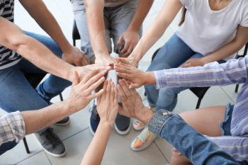 Young people holding hands together at group therapy session�