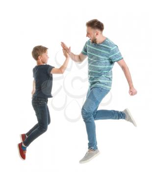 Jumping father and son giving each other high-five on white background�