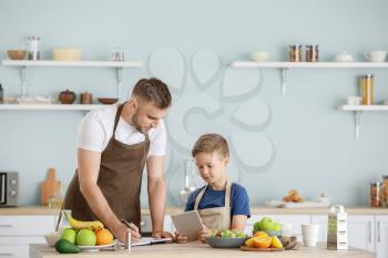 Portrait of happy father and son cooking in kitchen�