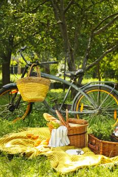 Bicycle and wicker baskets with tasty food and drink for romantic picnic in park�