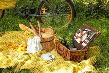 Wicker baskets with tasty food and drink for romantic picnic in park�