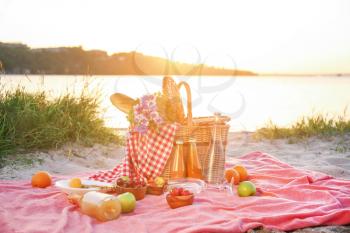 Wicker basket with tasty food and drink for romantic picnic near river�