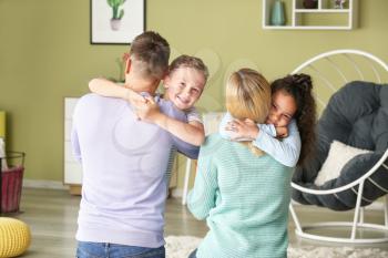 Happy couple with little adopted children at home�