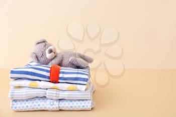 Stack of baby clothes on color background�
