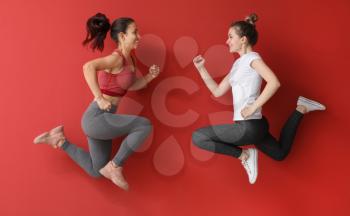 Jumping sporty women on color background�