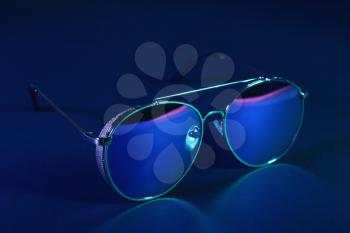 Stylish modern sunglasses on dark color background�