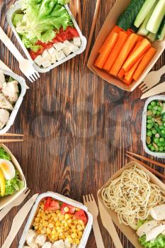 Containers with delicious food on wooden background�