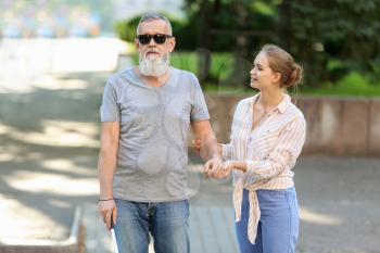 Woman helping blind mature man to cross road�