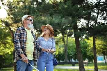 Blind mature man with his daughter walking in park�