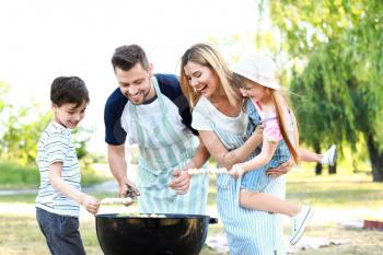 Happy family cooking tasty food on barbecue grill outdoors�