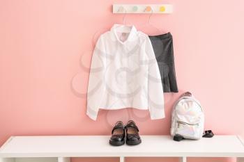Stylish school uniform with backpack and shoes in room�
