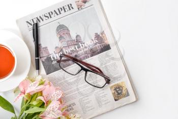 Newspaper, flowers and cup of tea on white background�