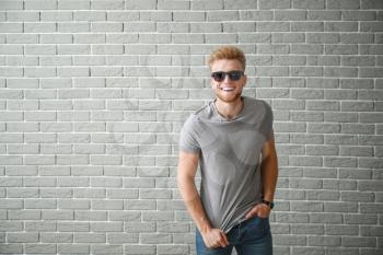 Man in stylish t-shirt near brick wall�