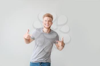 Man pointing at his t-shirt against light background�