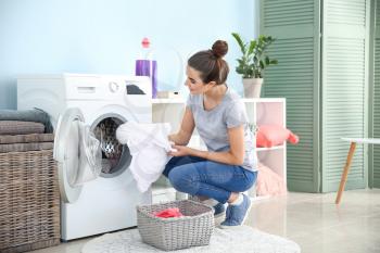 Beautiful young woman doing laundry at home�