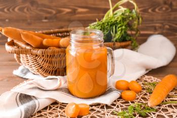 Mason jar of tasty carrot juice on table�
