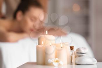 Beautiful burning candles with stones and essential oil on table in spa salon�