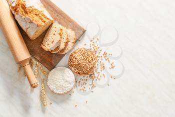 Rolling pin with fresh bread, wheat grains and flour on light background�