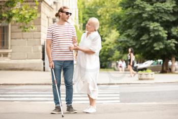 Blind young man with mother walking outdoors�