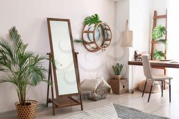 Interior of beautiful comfortable living room with big mirror, table and houseplant�