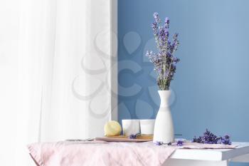 Beautiful lavender flowers in vase on table in room�