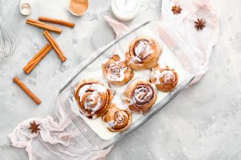 Baking tray with tasty cinnamon buns on grunge background�