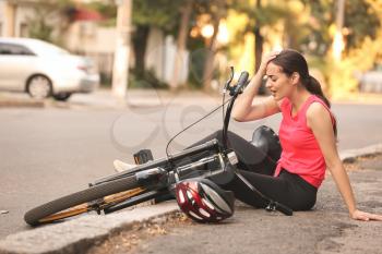 Sporty young woman fallen off her bicycle outdoors�