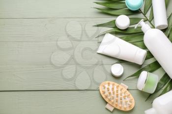 Set of cosmetic products and palm leaf on wooden background�