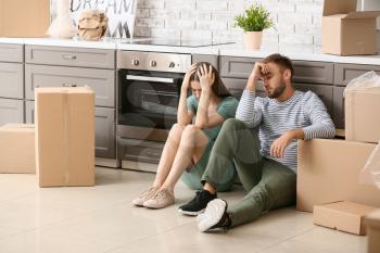 Tired couple sitting on floor after moving into new house�