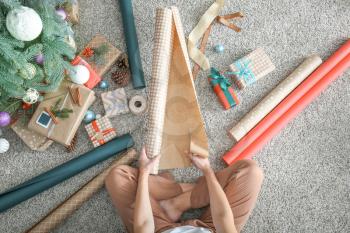 Woman making Christmas gift on floor, top view�