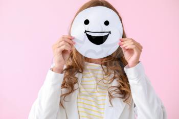 Woman hiding face behind  emoticon on color background�