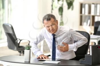 Mature man suffering from heart attack in office�