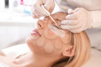 Young woman undergoing procedure of eyelashes lamination in beauty salon�