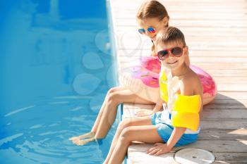 Cute little children sitting near swimming pool�