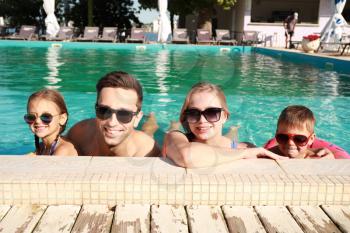 Happy family in swimming pool on summer day�