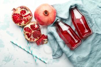 Composition with bottles of fresh pomegranate juice on light background�