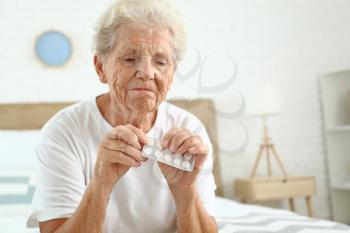 Elderly woman with pills at home�