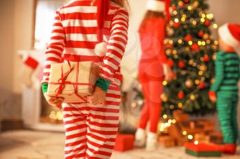 Little girl hiding gift behind her back on Christmas eve�