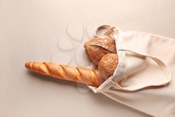 Eco bag with fresh bread on grey background�