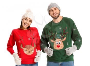 Young couple in Christmas sweaters on white background�