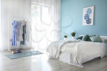 Interior of modern bedroom with big window and clothes rack�