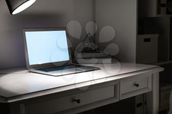 Modern workplace with laptop in evening�