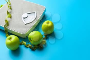 Scales, apples and measuring tape on color background. Weight loss concept�